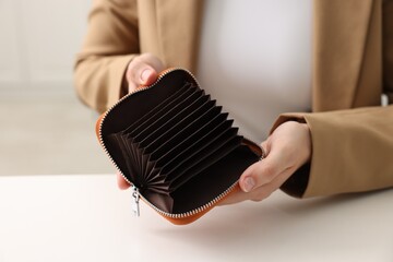 Woman with empty wallet at white table, closeup