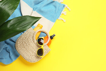 Flat lay composition with beach towel and other summer accessories on yellow background. Space for...