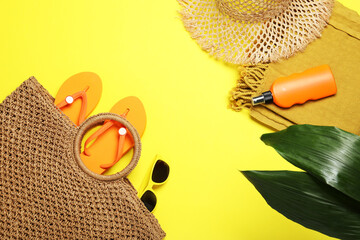 Flat lay composition with beach towel and other summer accessories on yellow background