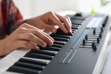 Man working with MIDI keyboard at table indoors, closeup