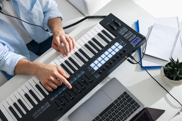 Man working with MIDI keyboard at white table indoors, above view