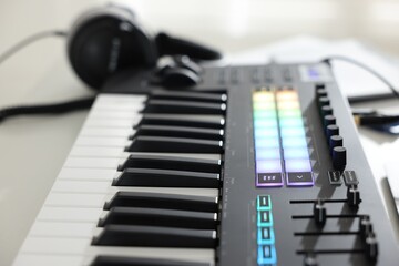 MIDI keyboard and headphones on white table, closeup