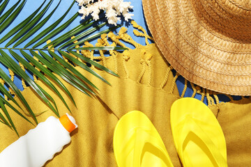 Beach accessories and palm leaf on blue background, flat lay