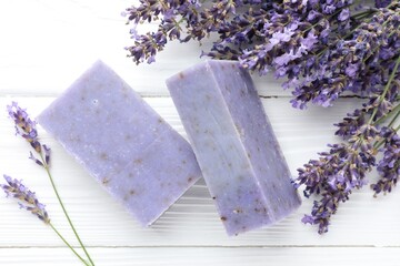 Soap bars and lavender flowers on white wooden table, flat lay