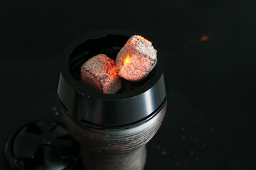 Smoldering charcoal cubes in hookah holder on dark background, closeup