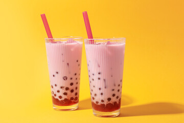 Tasty milk bubble tea in glasses on orange background