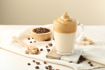 Delicious dalgona coffee in glass cup, beans and brown sugar on light table