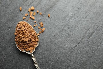 Spoon with instant coffee on black table, top view. Space for text