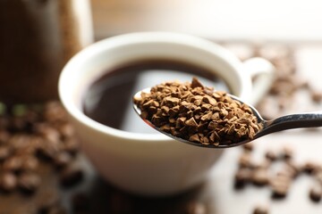 Spoon with instant coffee on blurred background, closeup