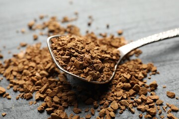 Spoon with instant coffee on black table, closeup