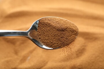 Spoon with aromatic instant coffee as background, closeup