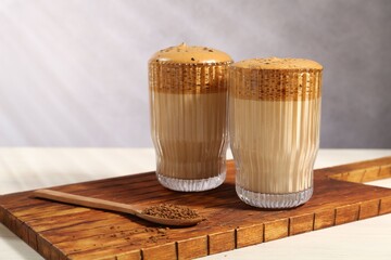 Delicious dalgona coffee in glasses and granules on light table, closeup