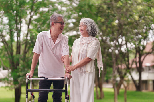 Older Asian couple happy walk park support walker retirement wellness healthy life