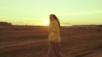 a girl jogging at sunset in the glare of sun, man likes to do fitness, sports jogging marathon at...