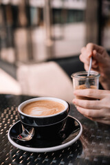 Enjoying a relaxing coffee while stirring sugar on a sunny cafe terrace in the city