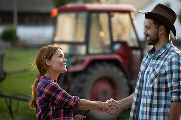 Friendly handshake between two farmers outdoors at sunset