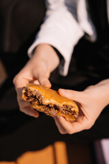 Delicious burger held by hands on a sunny day with a casual setting in the background