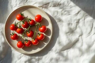 A photo of cherry tomatoes on a beige plate, on a white linen tablecloth, with sunlight from the window creating a play of shadows, embodying a minimalist aesthetic. 