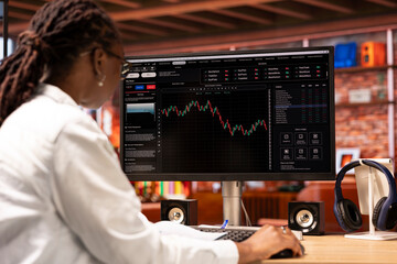 Day trader using PC monitor, purchasing stocks that might perform well and selling ones that might...