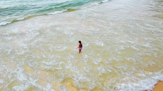 Little girl plays with the sea and jumps on the waves at Naithon Beach, Phuket