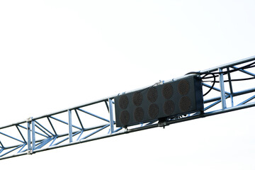 Close-up of a digital start light system mounted on a metal truss above a racing track, against a...