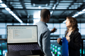 Focus on laptop in data center used by software developers refining server virtualization...