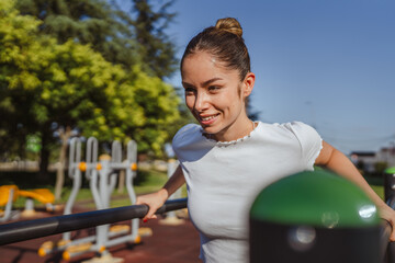 Sporty fit adult woman working out triceps and biceps at gym park