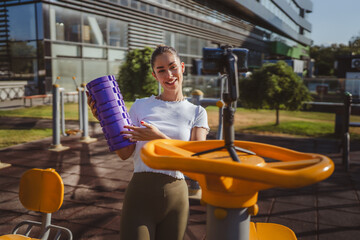 sportswoman at outdoor gym filming herself with foam roller on camera