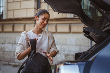 adult smiling woman pack her stuff into car trunk on the street © Miljan Živković