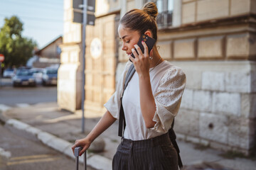 caucasian adult woman with suitcase talk on on the street