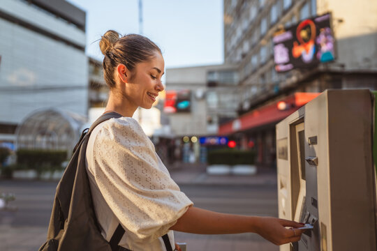 woman with baggage using credit card and withdrawing cash at the ATM