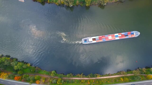 Aerial view of large barge with containers cruising through moselle river in Germany near Senheim village.