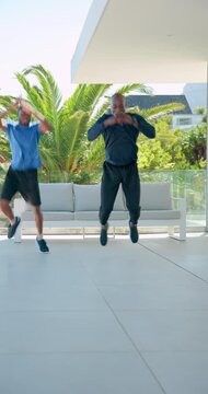 Vertical video: African American father-son bouncing on patio sparking tuck jumps twists high knees