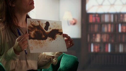 Armed forces veteran in uniform sits with a therapist during counseling, viewing a Rorschach test...
