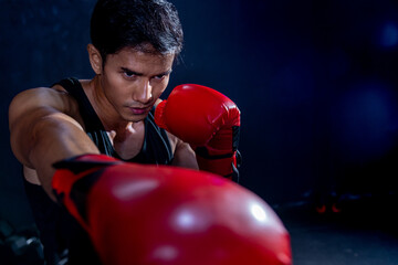 a man in activewear and red boxing gloves on black background performing a martial arts kick. sport...