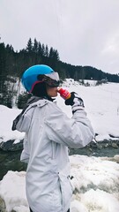 Narciarka w kasku pije z czerwonej butelki