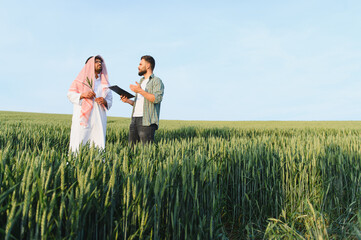 Arab businessman and agronomist discussing in wheat field