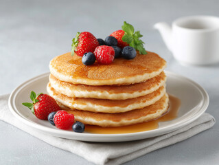 Delicious stack of fluffy pancakes topped with fresh berries and syrup on a light textured background