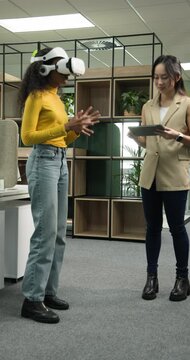 Vertical video: Tester wearing VR headset pinching while lead tapping tablet adjusting settings