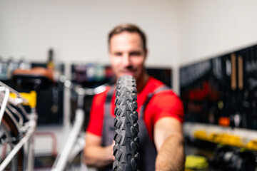 Replacing old bicycle tire. Experienced serviceman holding damaged bike tire for replacement.