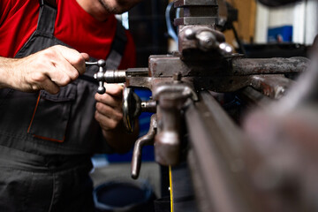 Metal worker processing steel material on lathe machine.