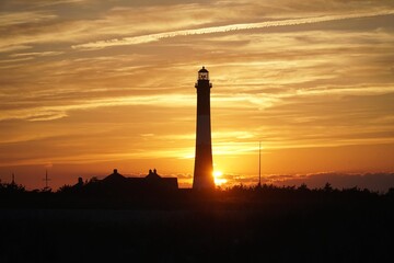Fire Island Lighthouse glowing warmly at sunset with vibrant sky