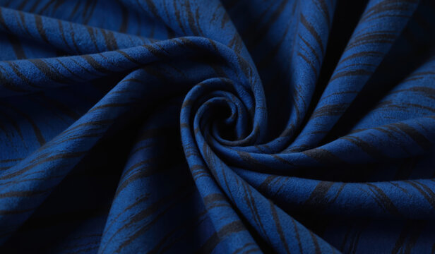 Close-up of vibrant blue fabric with geometric pattern of intersecting black lines. Fabric appears layered, edges and corners visible. Striking blue hue dominates, abstract design.