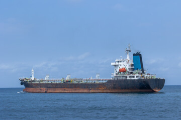 A large bulk carrier cargo ship sailing on the open ocean under a blue sky