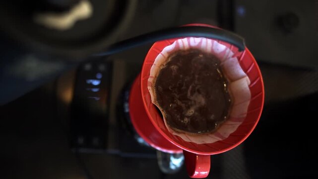 A barista prepares pour over coffee using a V60 dripper with hot water and fresh ground beans. Manual brewing method in a warm, minimalist cafe setting.