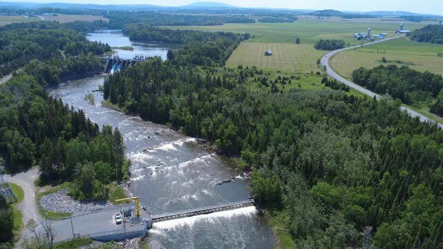 Drone footage of a salmon capture and counting trap installed on the Mitis River upstream of a hydroelectric dam, with farmland and agricultural fields in Price, Quebec, Canada.