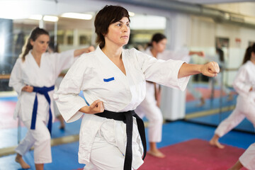 Women athletes learn practice of kata karate punches, hone fighting skills by repeated repetition....