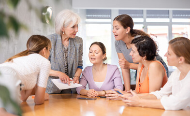 Interested senior woman participating in English language speaking club, communicating with group...