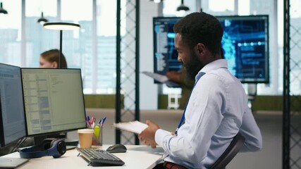 Admin in tech startup office using PC, compiling software patches to fix bugs, troubleshooting backend operations. IT expert running diagnostics, resolving system crashes via terminal, camera A