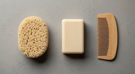 A minimalist shot of bathing essentials arranged in a line. A sponge, soap and a comb sit in a row